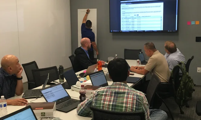 Stakeholders in a workshop room around a screen